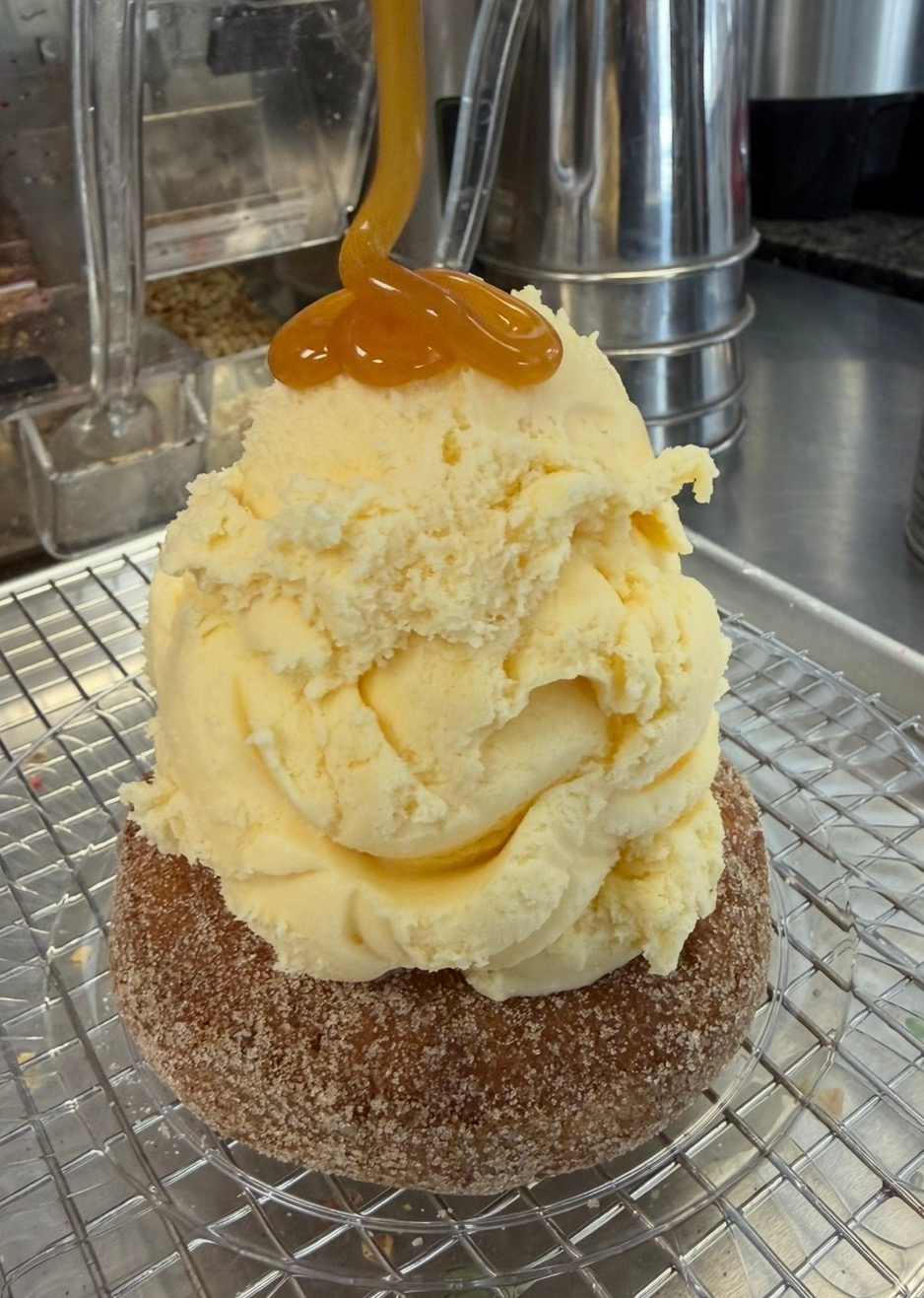 Large scoop of vanilla ice cream on a cinnamon-sugar rimmed glass, topped with caramel sauce.
