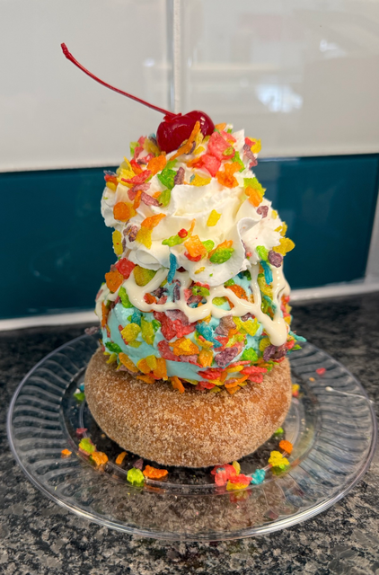 Hands holding a chocolate ice cream sundae topped with sprinkles in a glass bowl