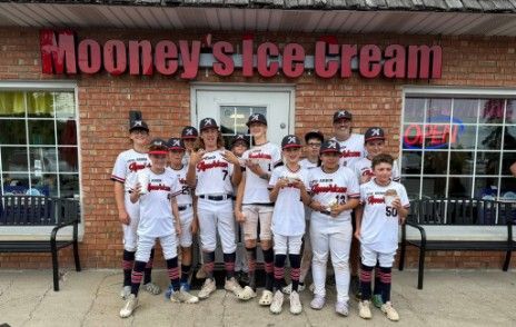 Youth baseball team posing outside Mooney’s Ice Cream storefront