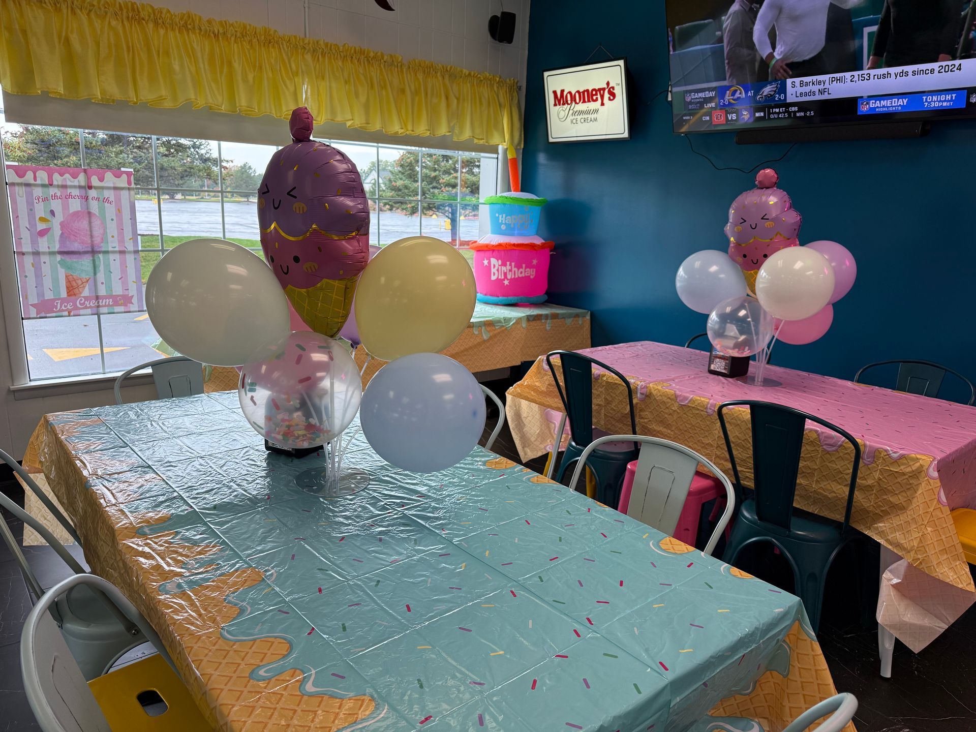 Family gathered around a birthday cake at a café table, with colorful balloons and smiles.