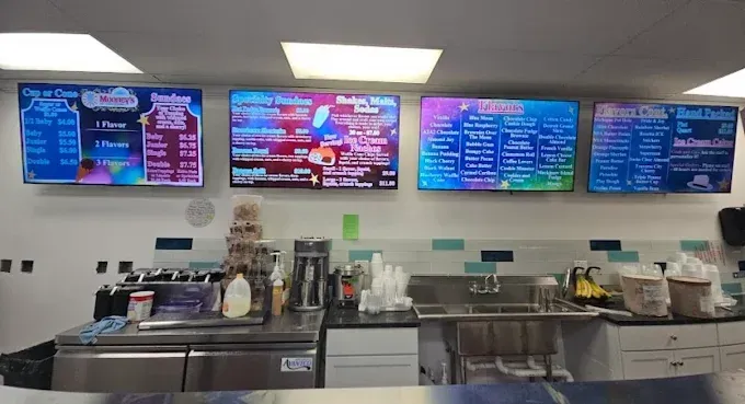 Dessert table with assorted ice cream sundaes and cakes in a pastel café setting