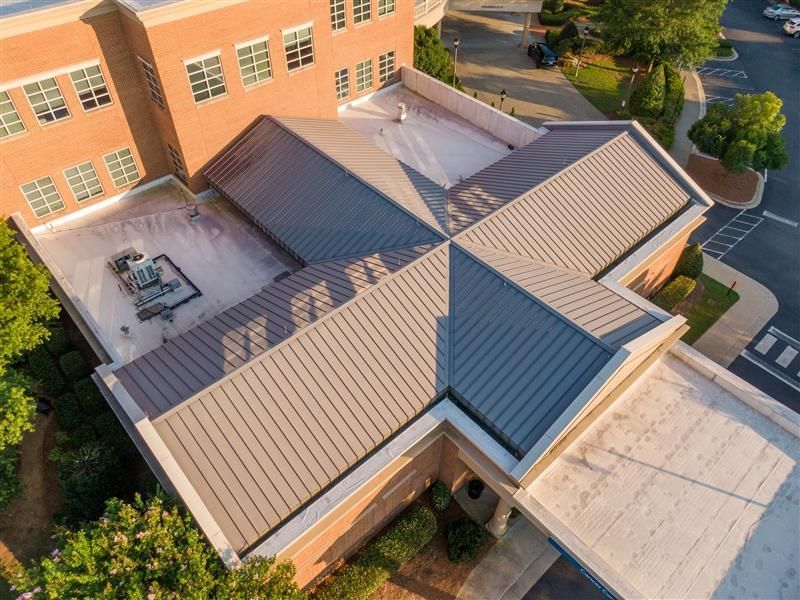 Aerial view of a building with a gray metal roof and red brick walls.