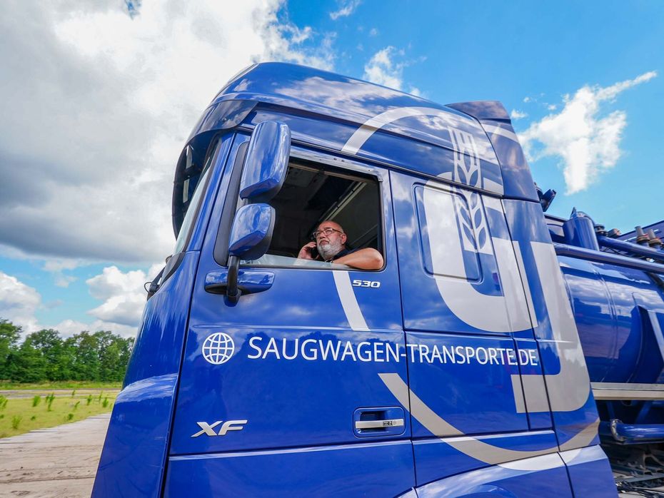 Ein Mann sitzt in einem großen blauen Saugtankwagen von Janssen Rhede