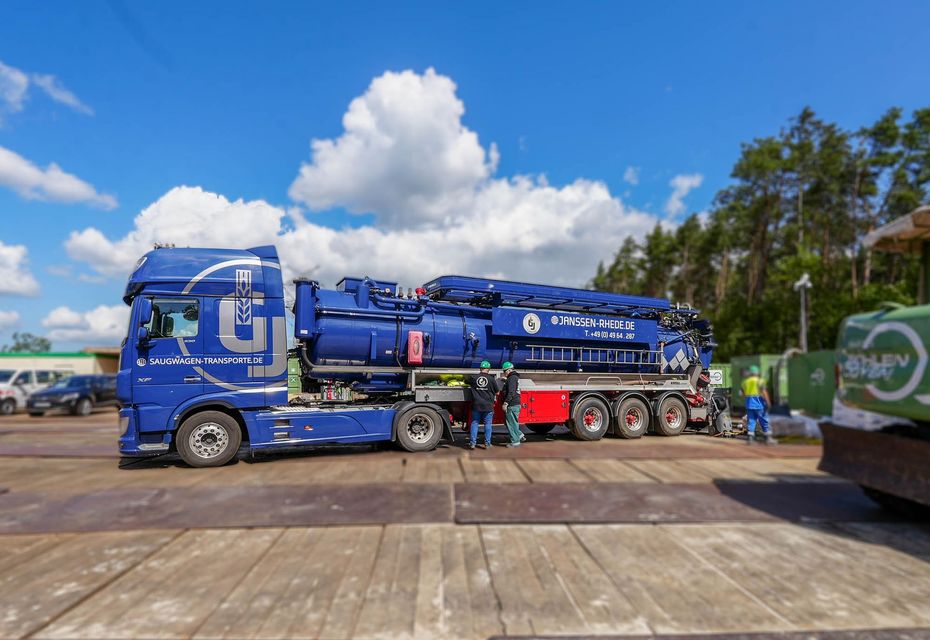 Ein großer blauer Saugtankwagen von der Seite mit Personen davor