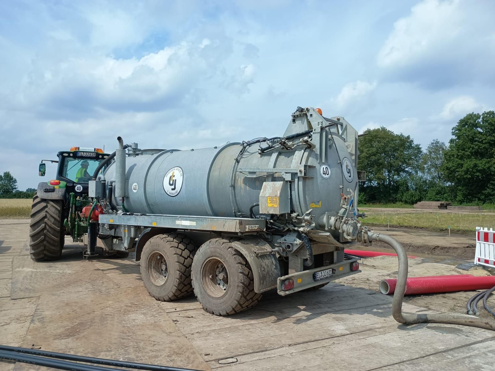 Ein Traktor steht vor einem Güllefass von Janssen Rhede, das befüllt wird.