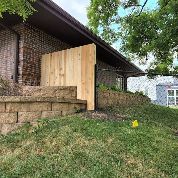 Wooden privacy fence installed beside a brick building's exterior.