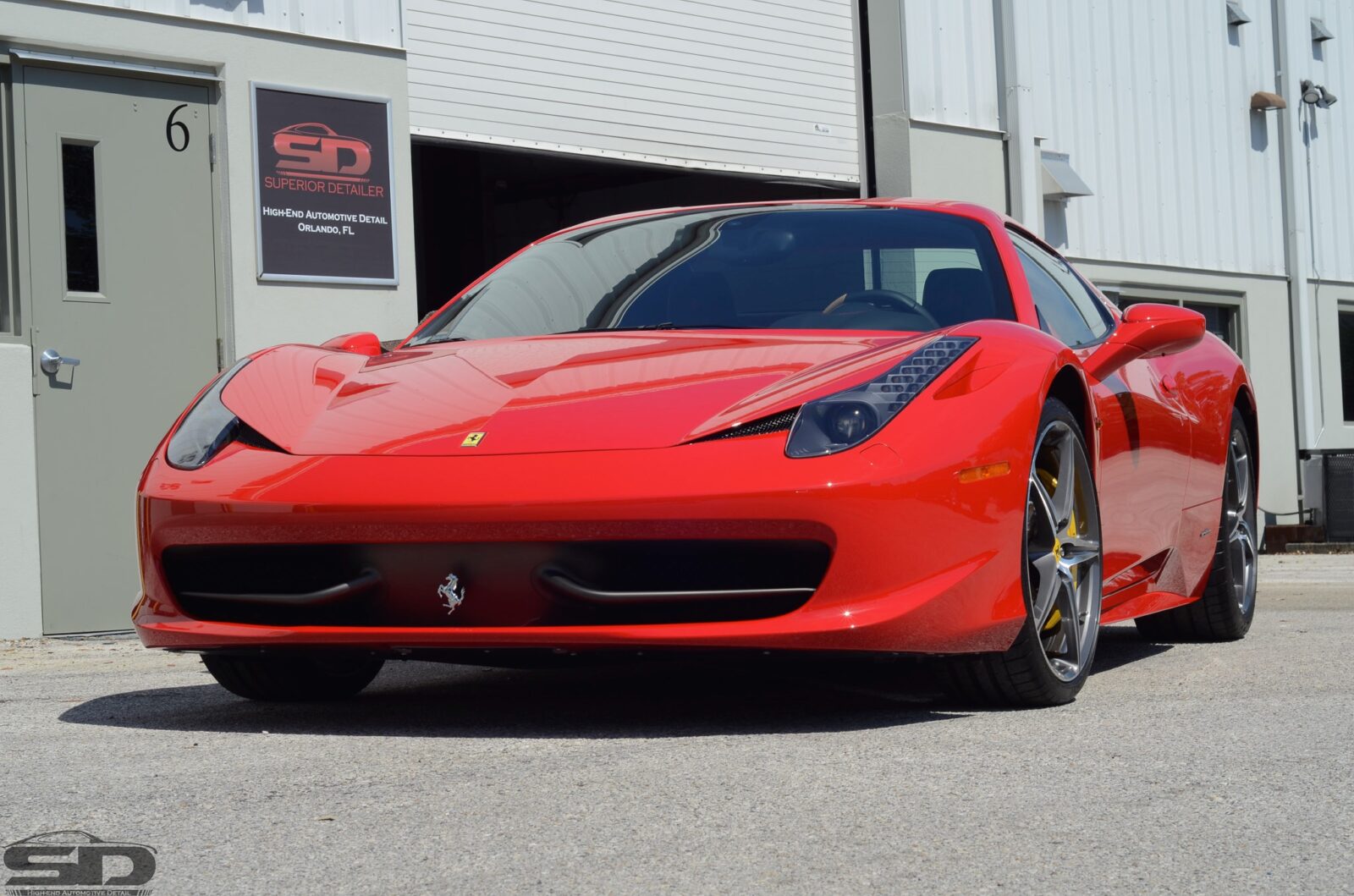 A red ferrari is parked in front of a building
