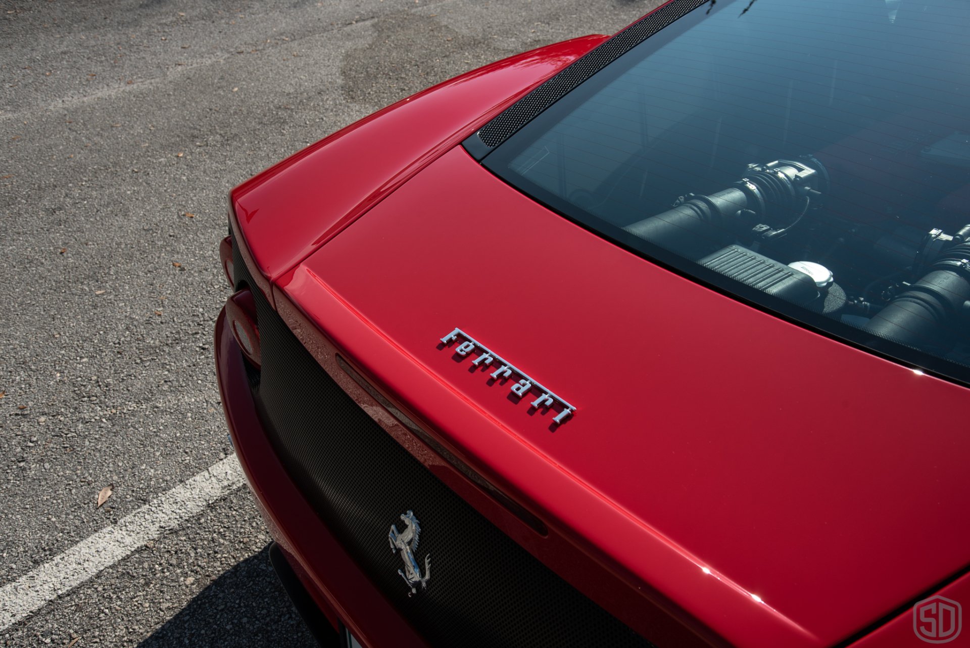A red ferrari is parked in a parking lot