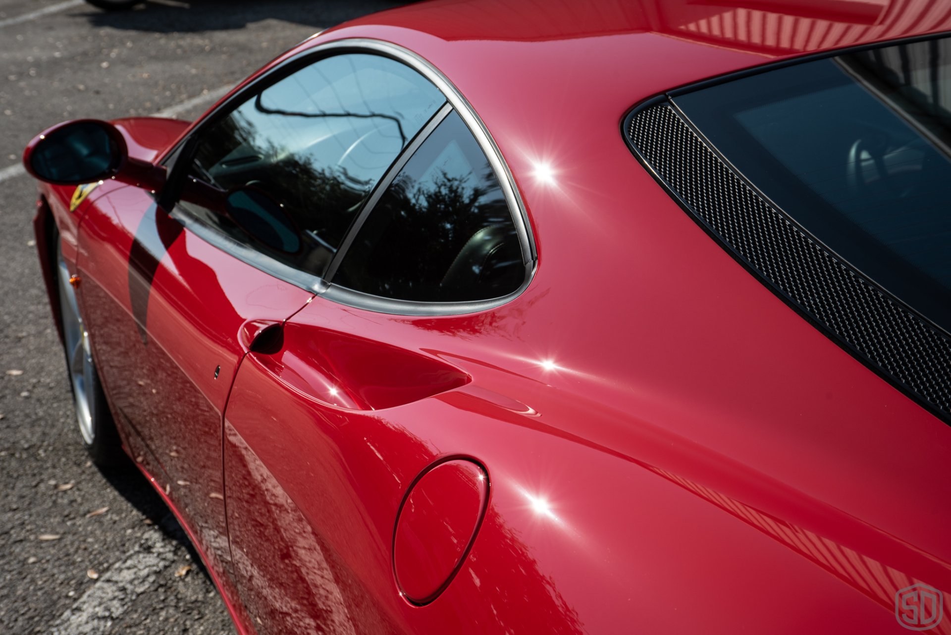 A red sports car is parked in a parking lot