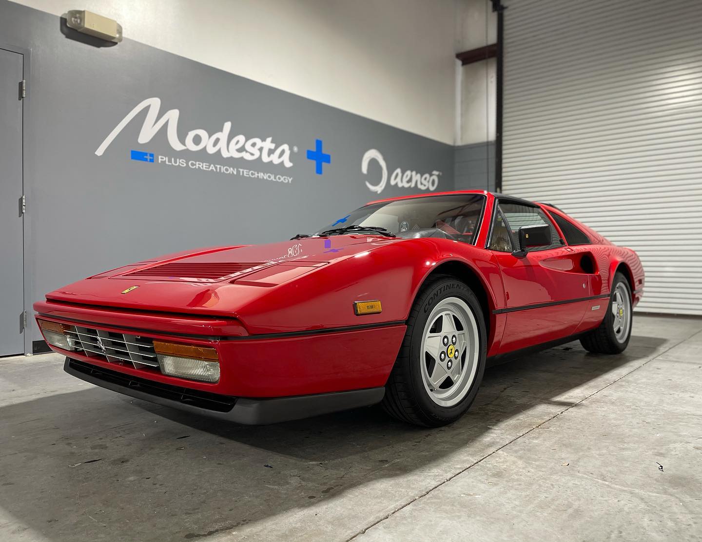 A red ferrari 328 gtb is parked in a garage.