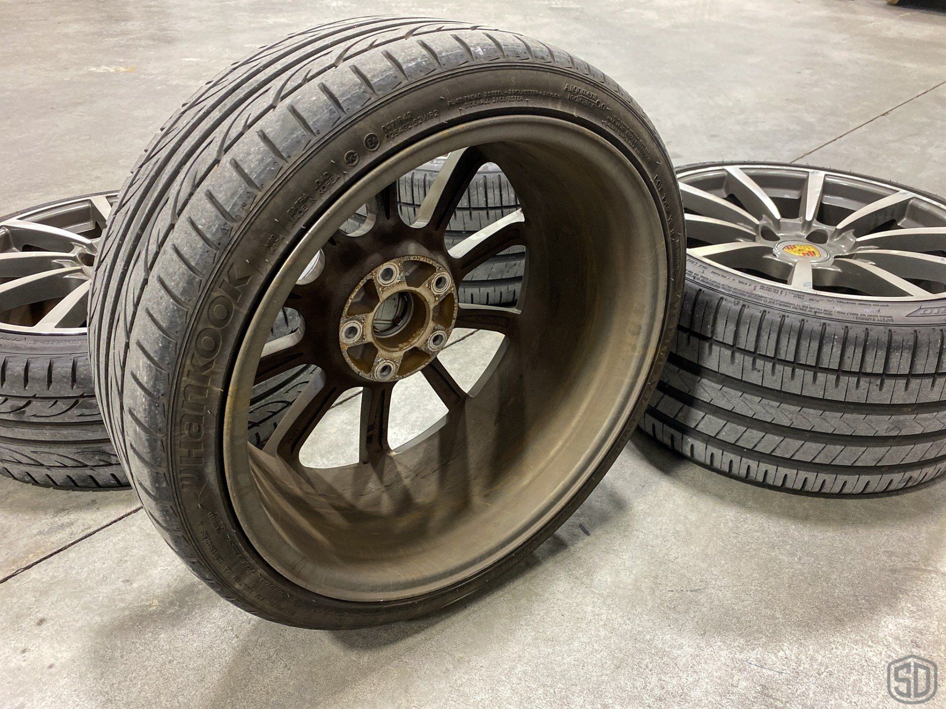 Three tires and wheels are sitting on a concrete floor.