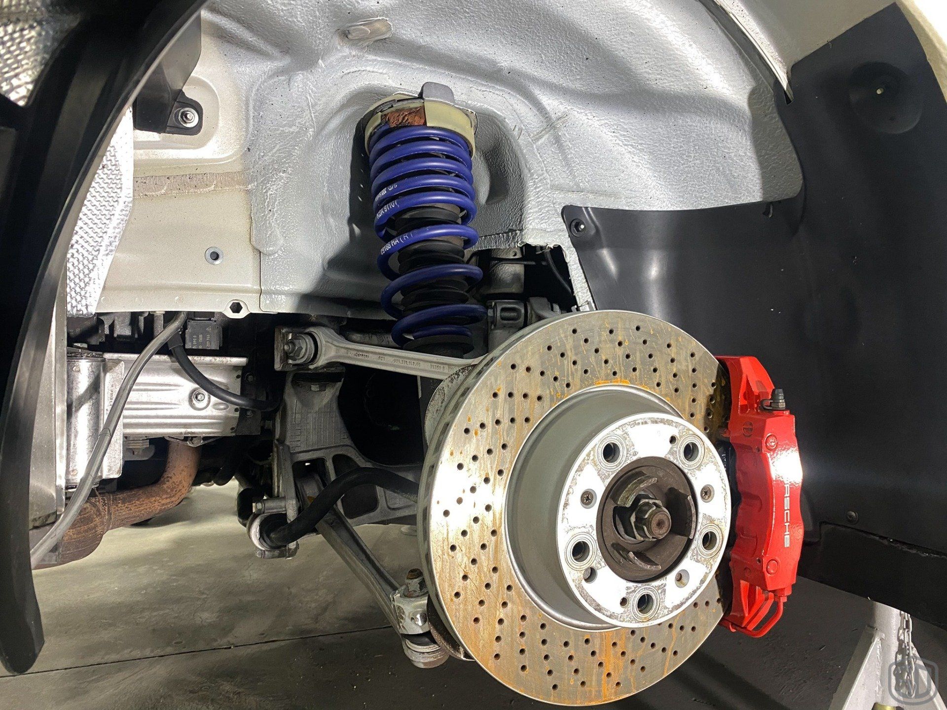 A close up of the underside of a car with a brake disc and shock absorber.