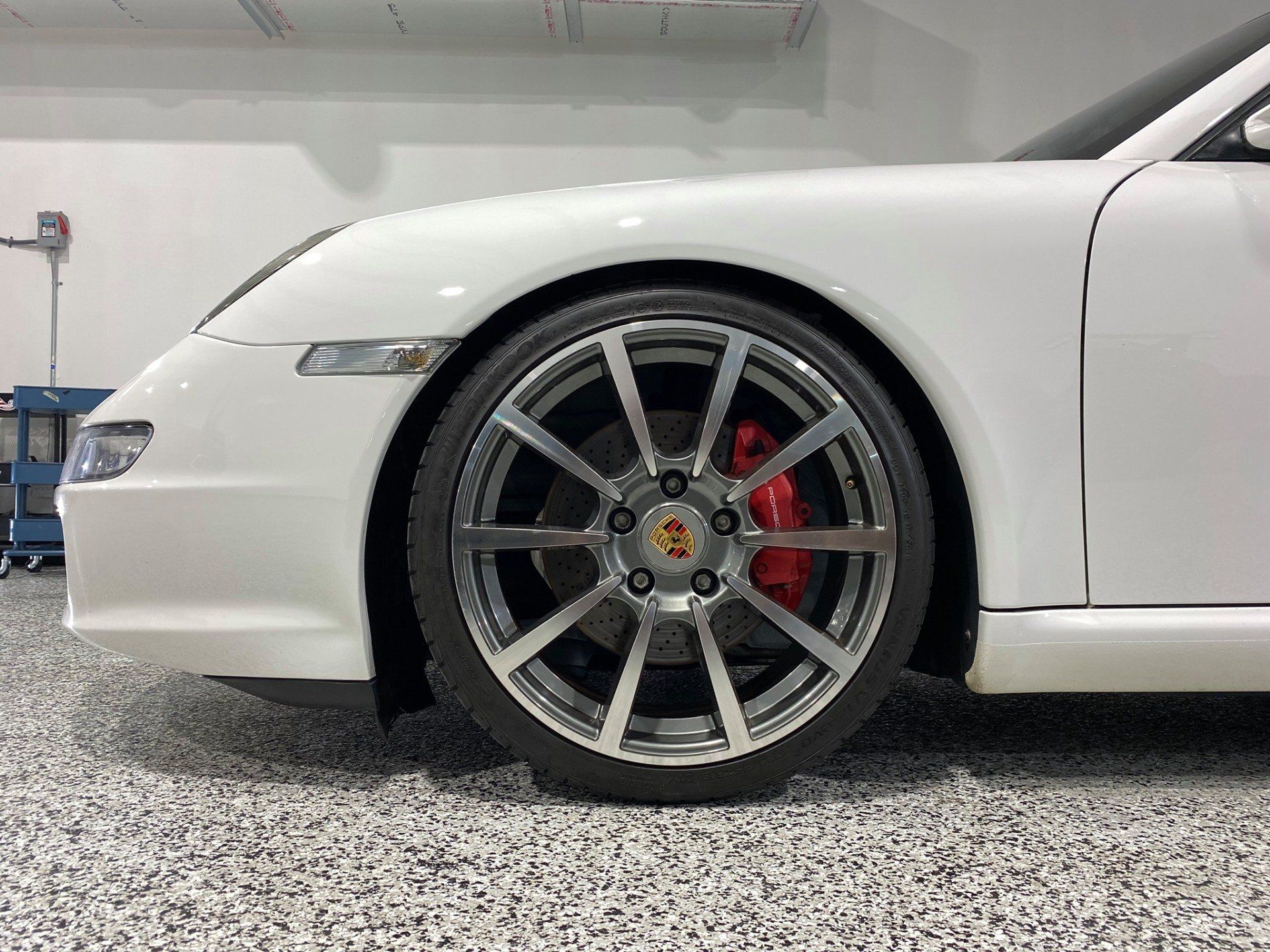 A white porsche 911 is parked in a garage.