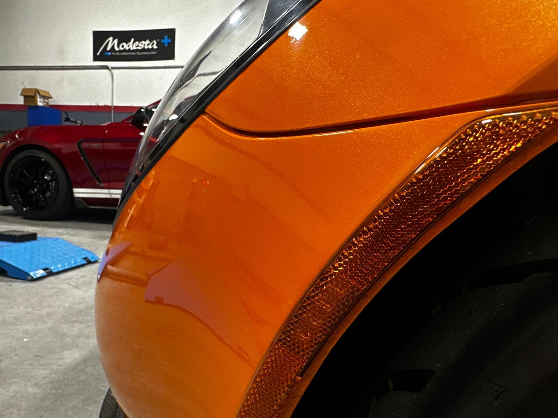A close up of an orange car in a garage