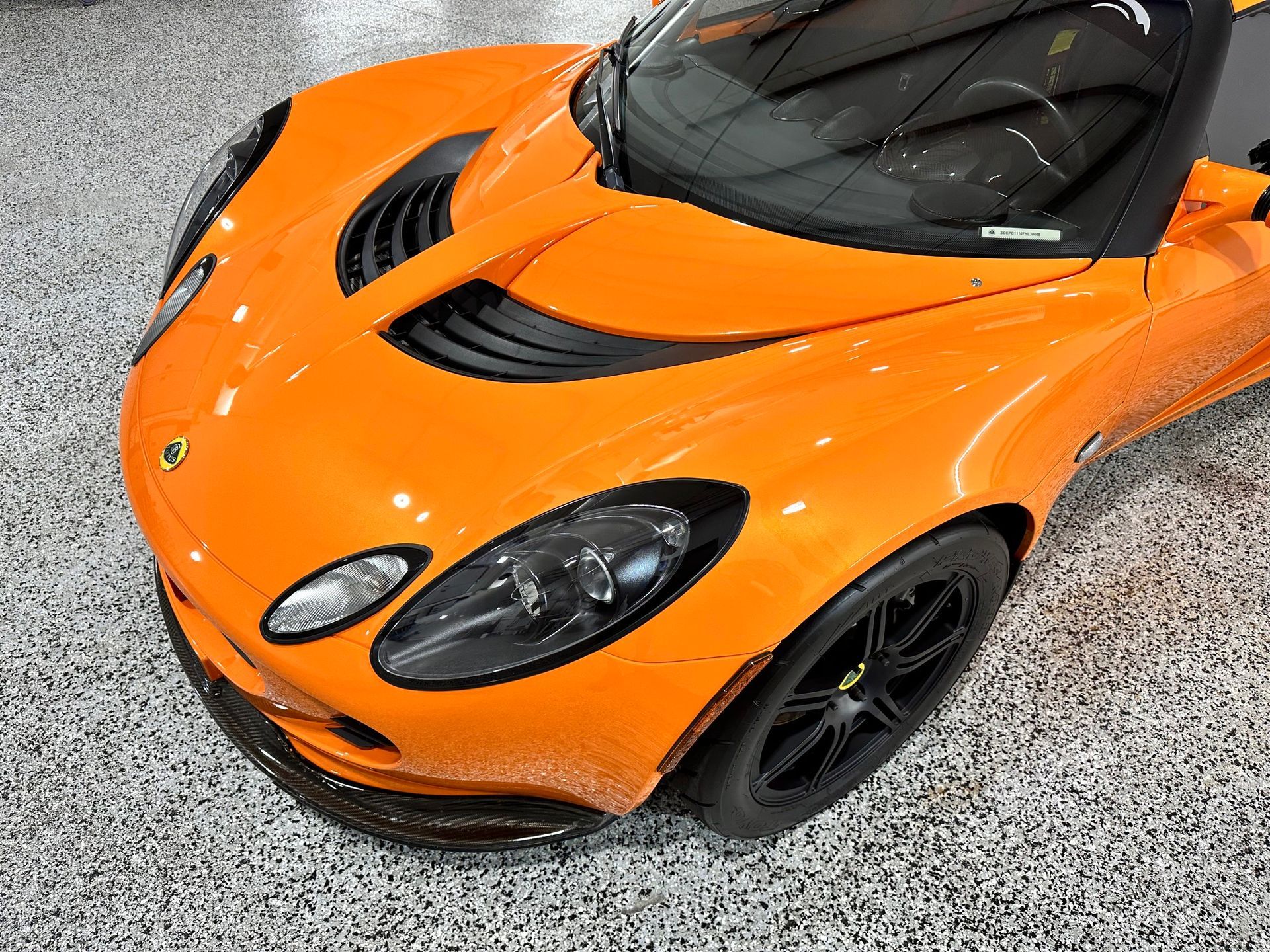 An orange sports car is parked in a garage.