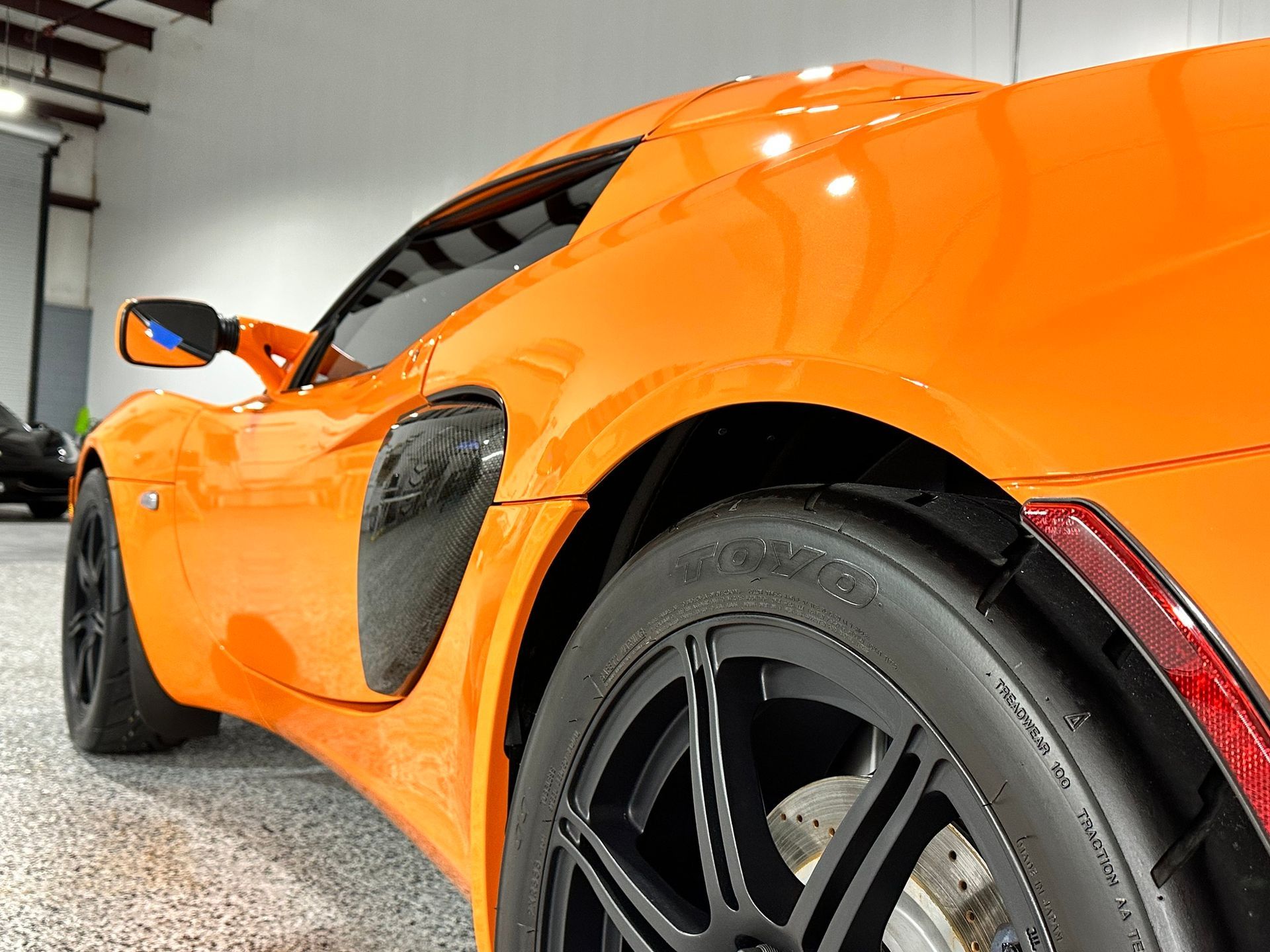 An orange sports car is parked in a garage.