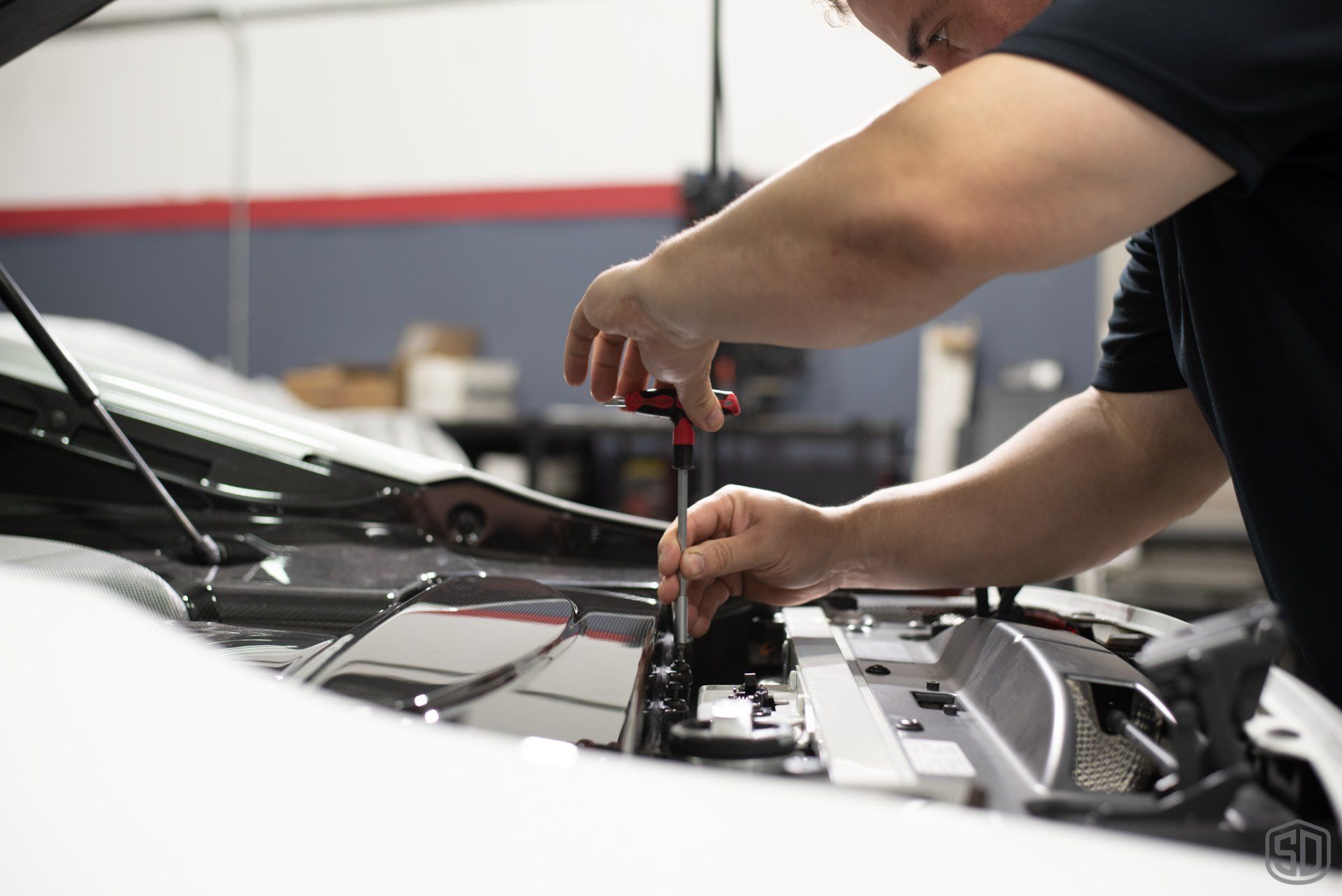 A man is working on the engine of a car in a garage.