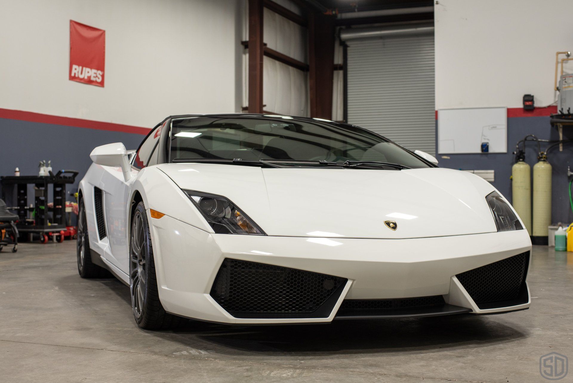 A white lamborghini gallardo is parked in a garage.