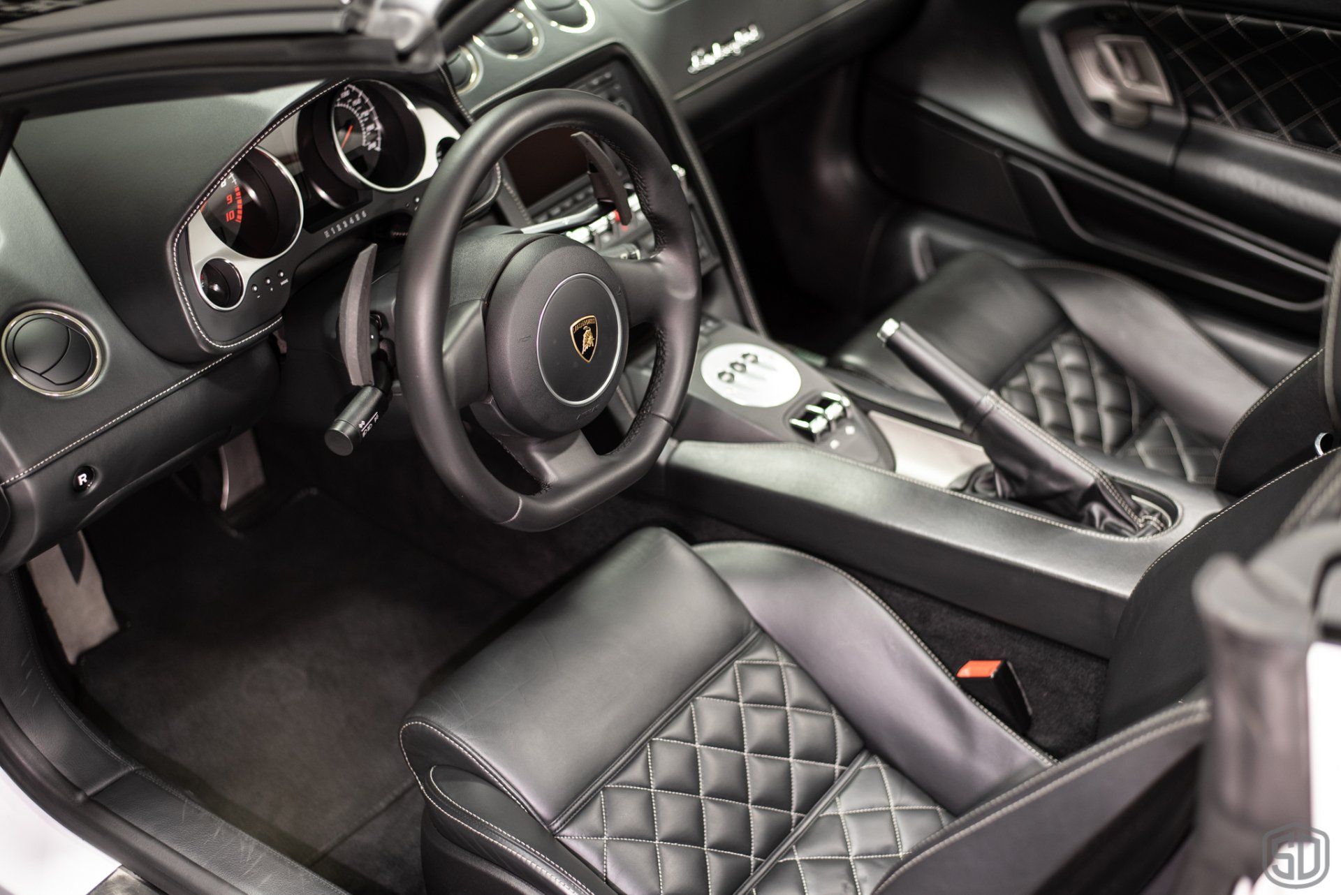 The interior of a lamborghini with black seats and a steering wheel