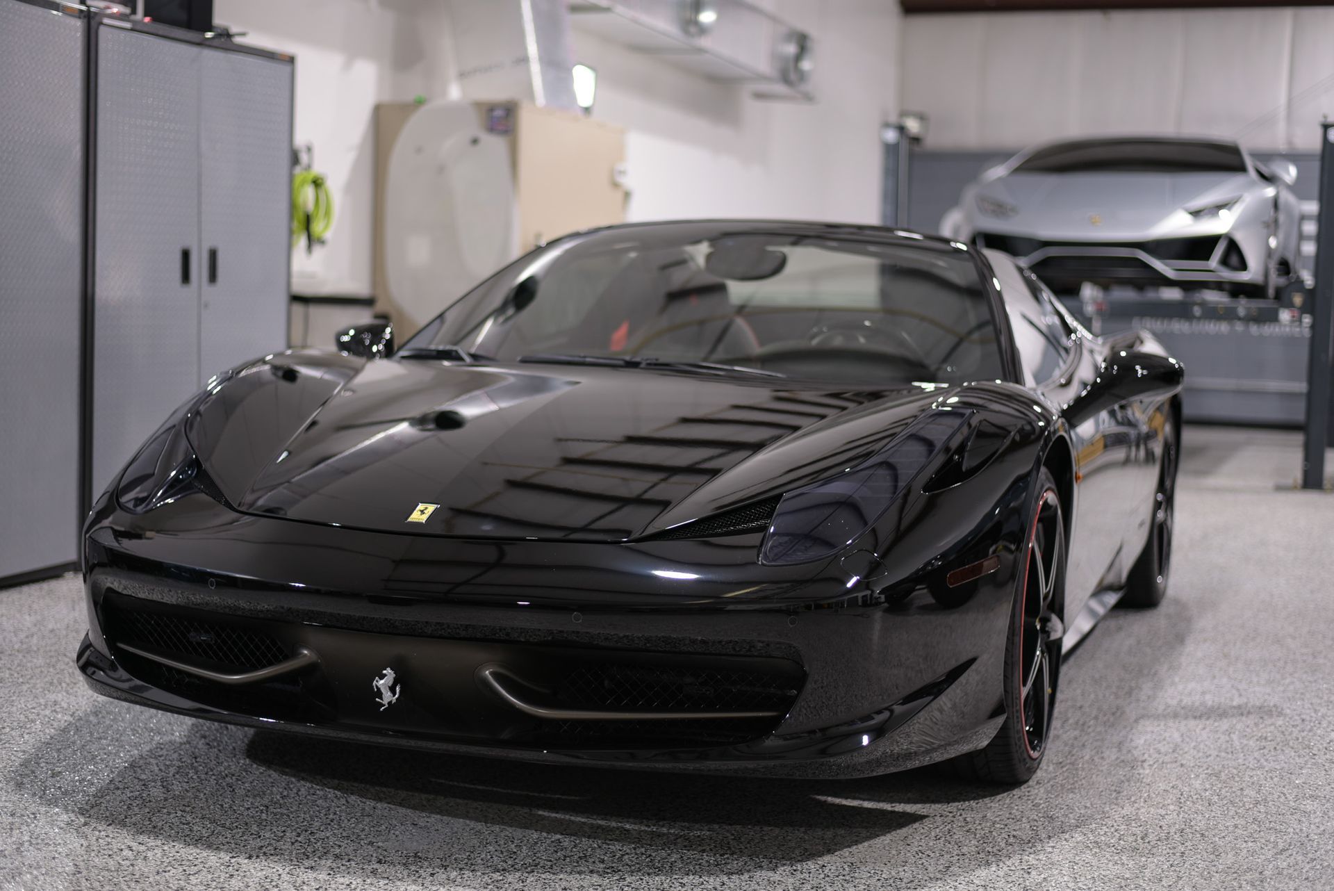 A black ferrari sports car is parked in a garage.