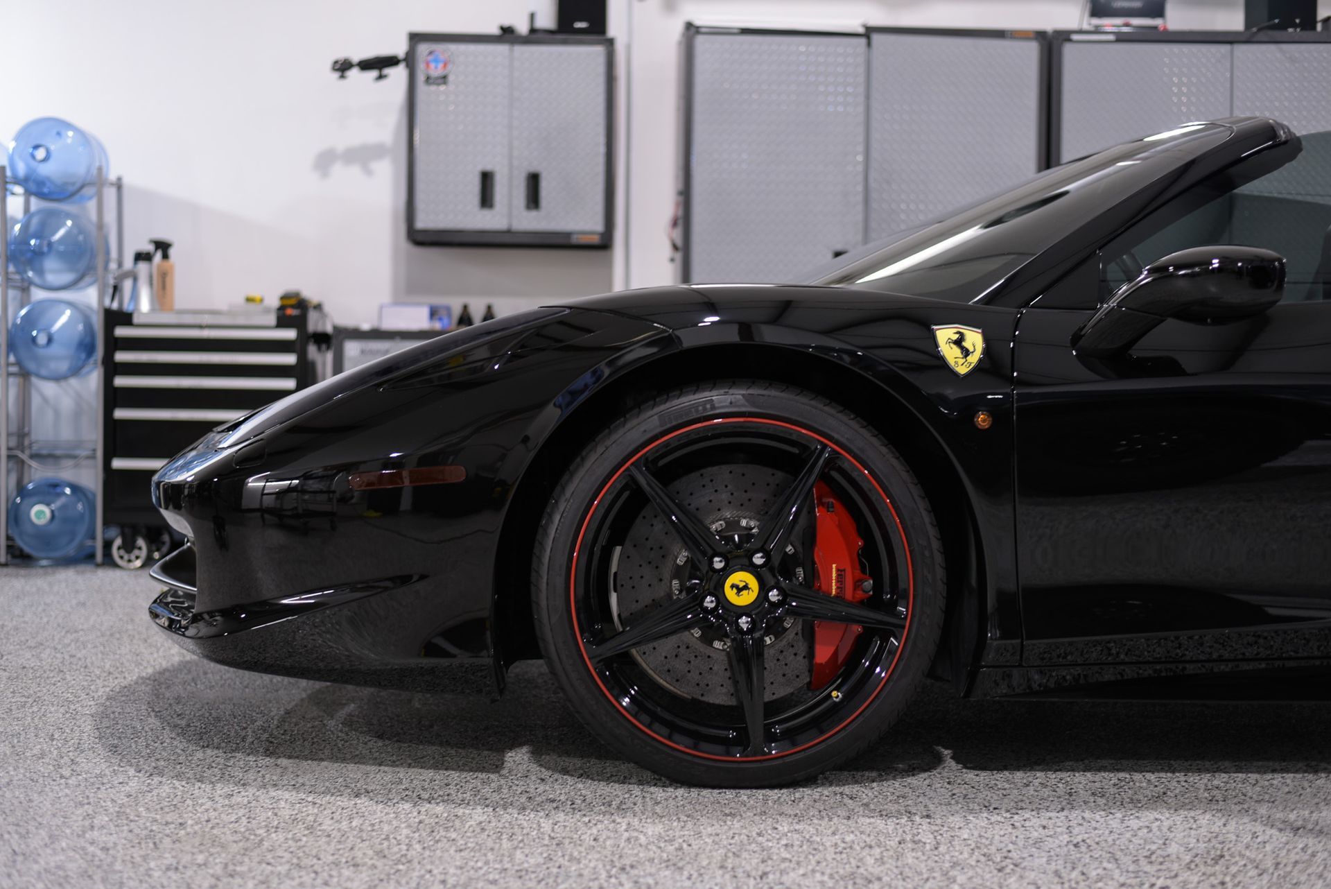 A black ferrari sports car is parked in a garage.