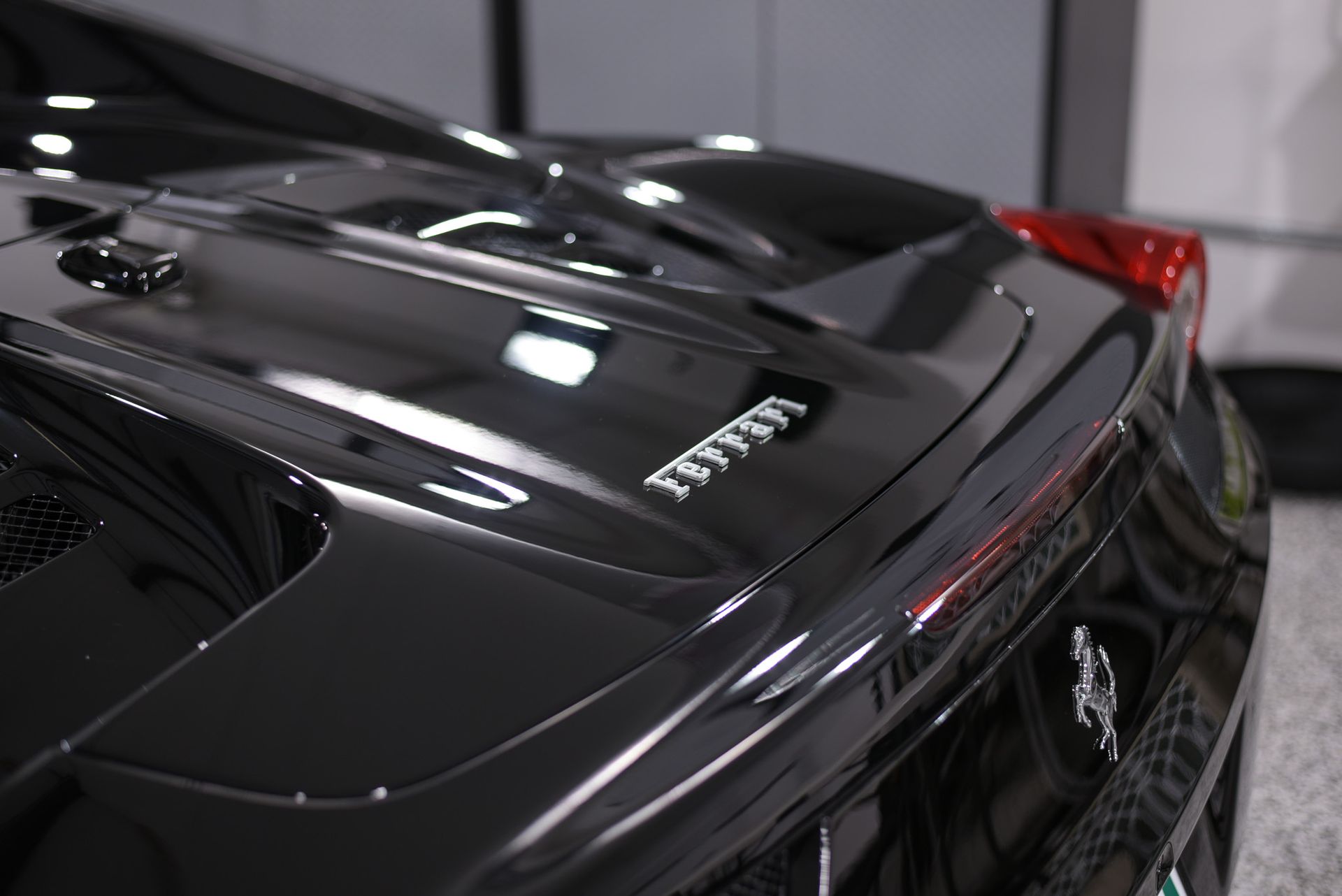 A black ferrari sports car is parked in a garage.