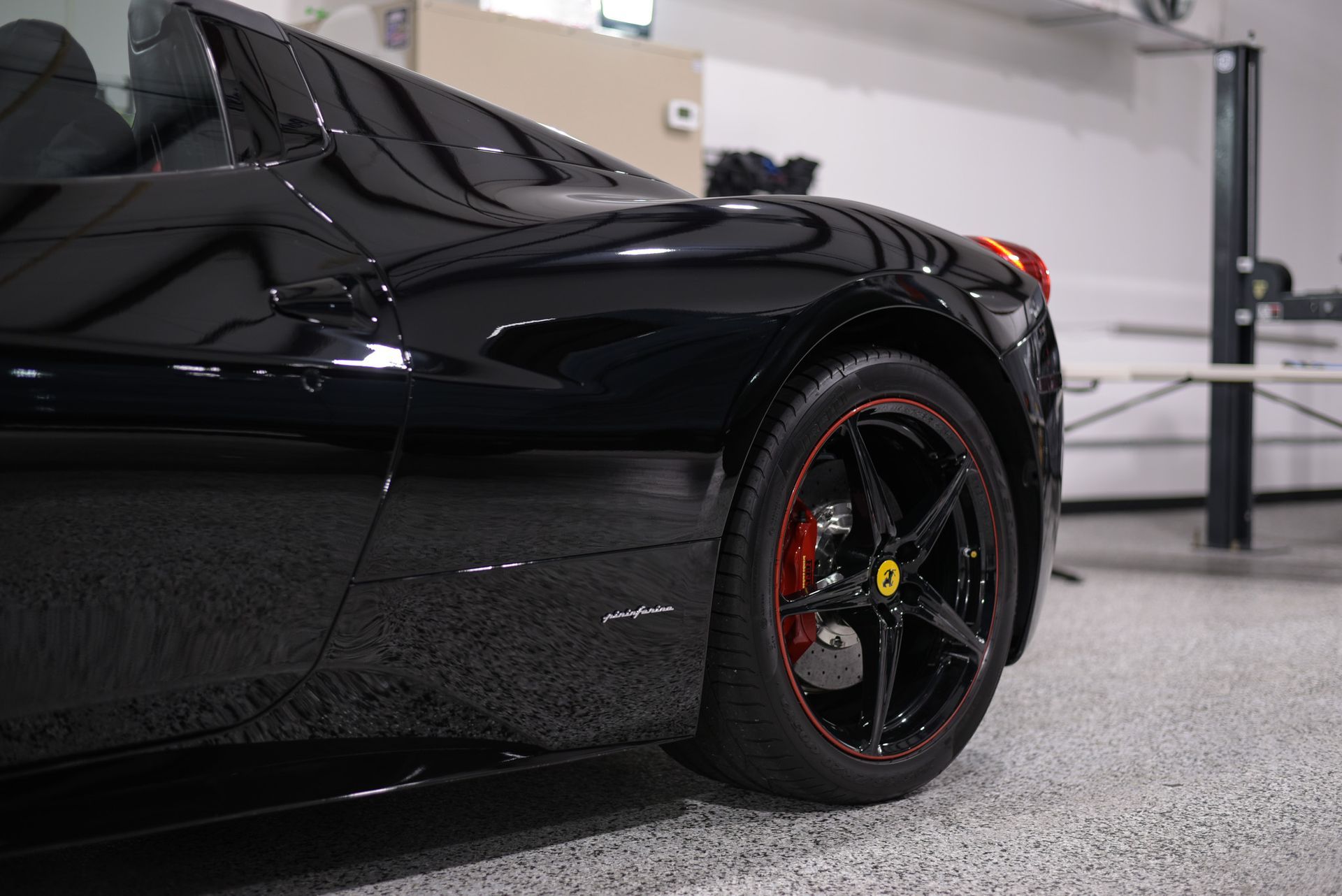 A black ferrari sports car is parked in a garage.