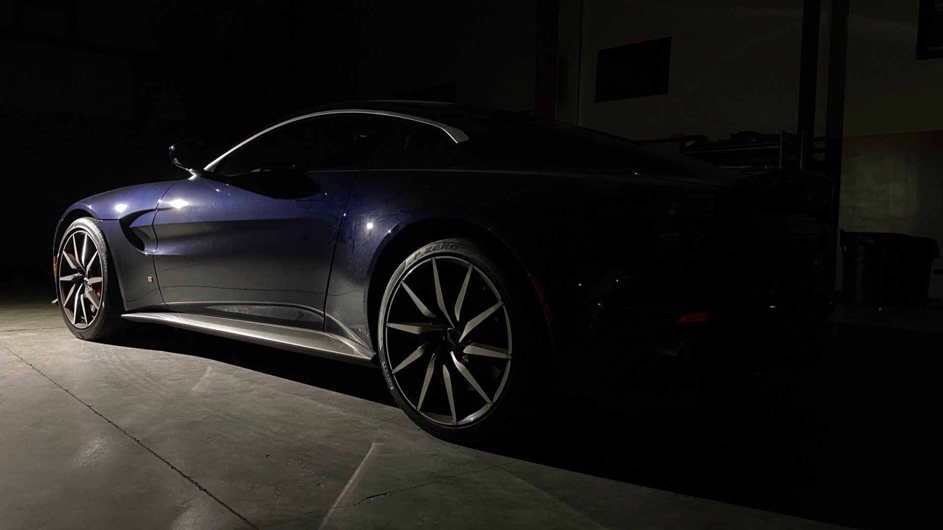 A blue sports car is parked in a dark parking lot.