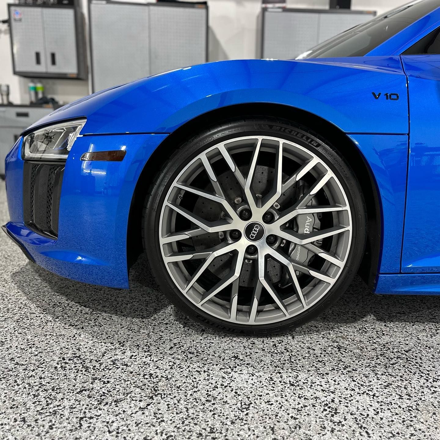 A blue audi r8 v10 is parked in a garage