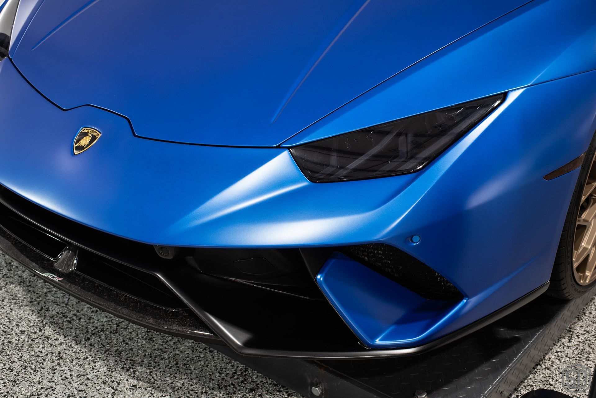 A close up of the front of a blue lamborghini huracan