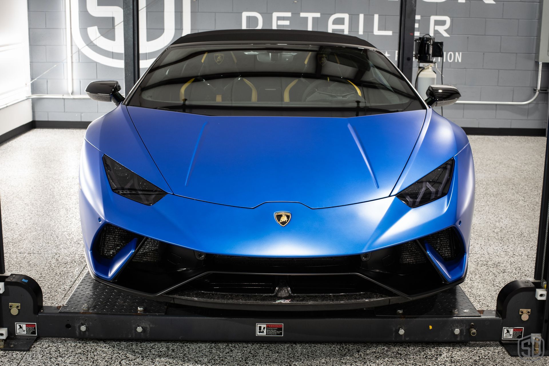 A blue lamborghini huracan is parked on a lift in a garage.