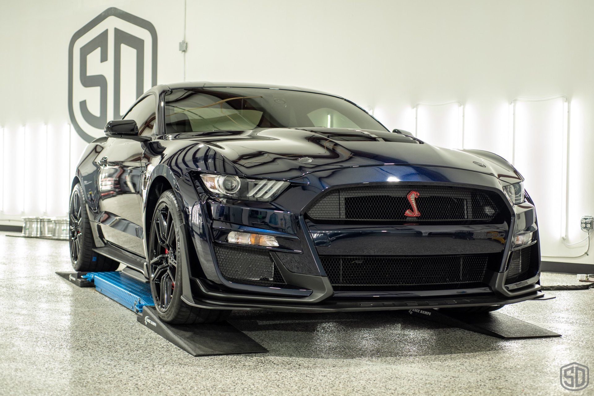 A black ford mustang is parked on a lift in a garage.