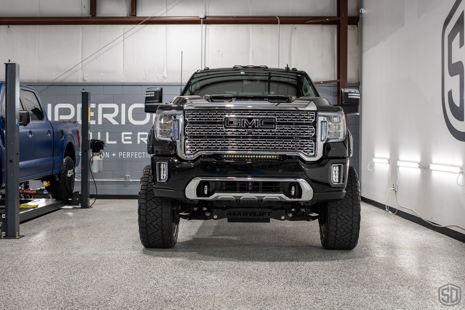 A black truck is parked in a garage on a lift.