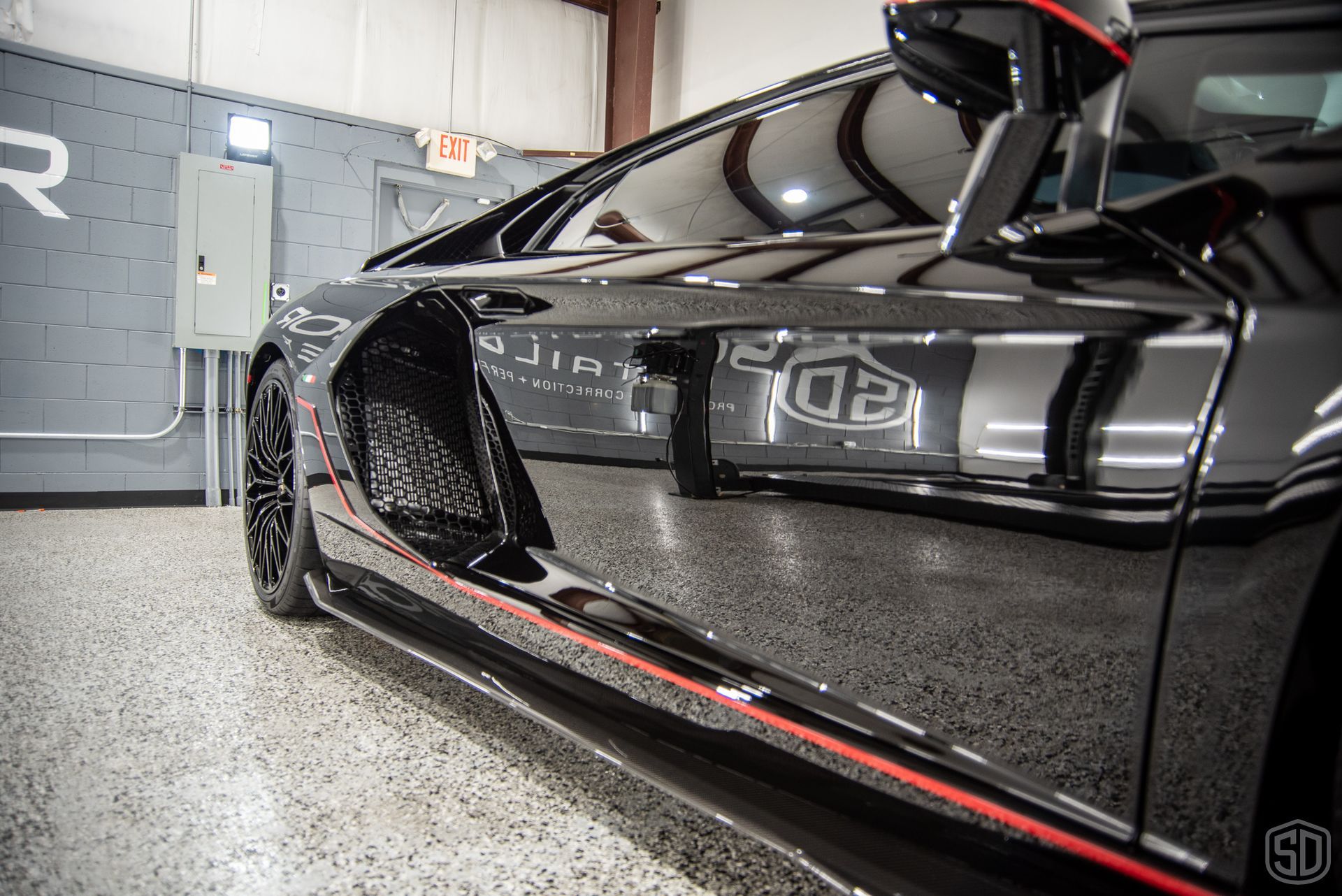A black sports car with red stripes on the side is parked in a garage.