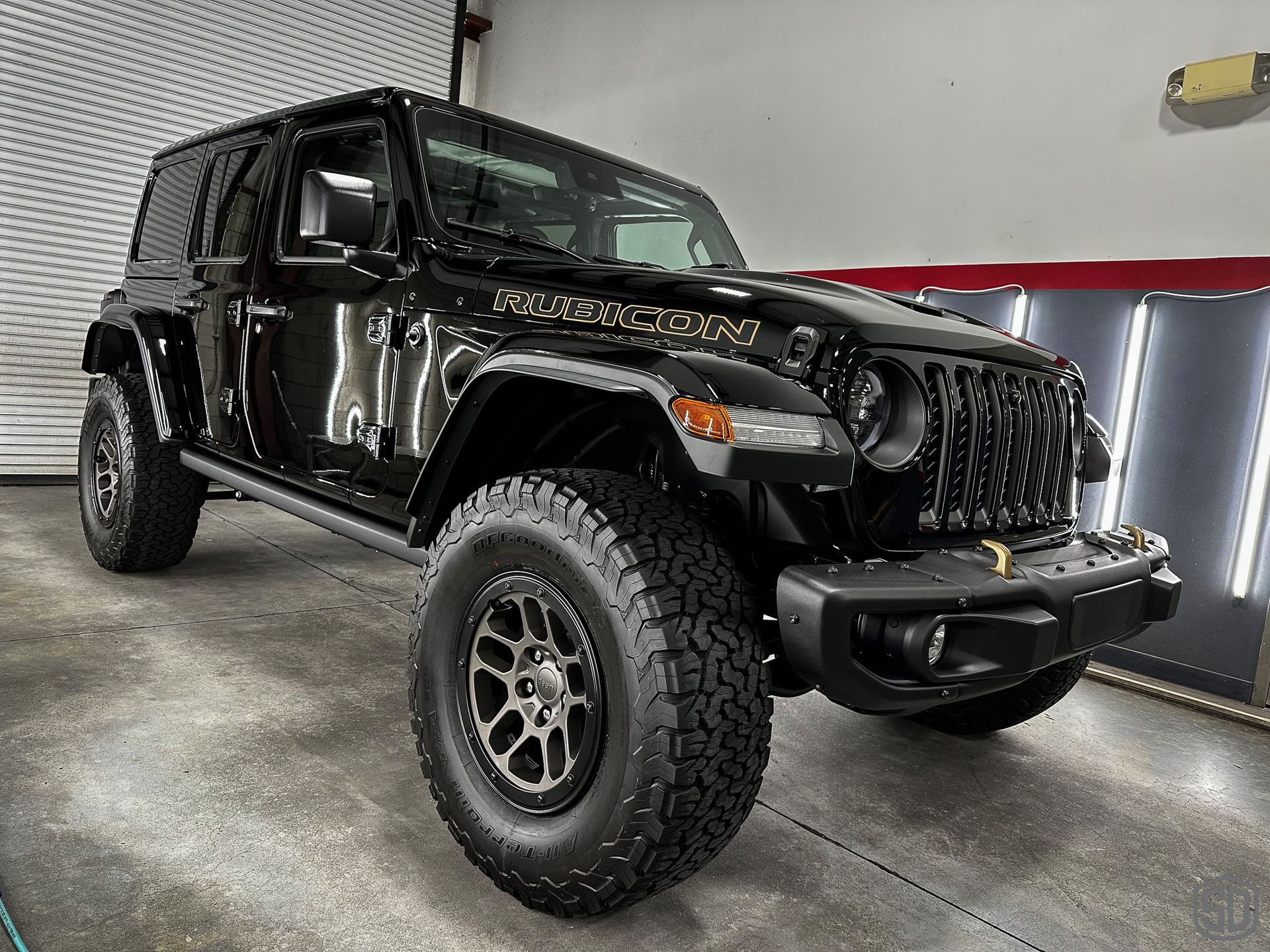 A black jeep wrangler is parked in a garage.