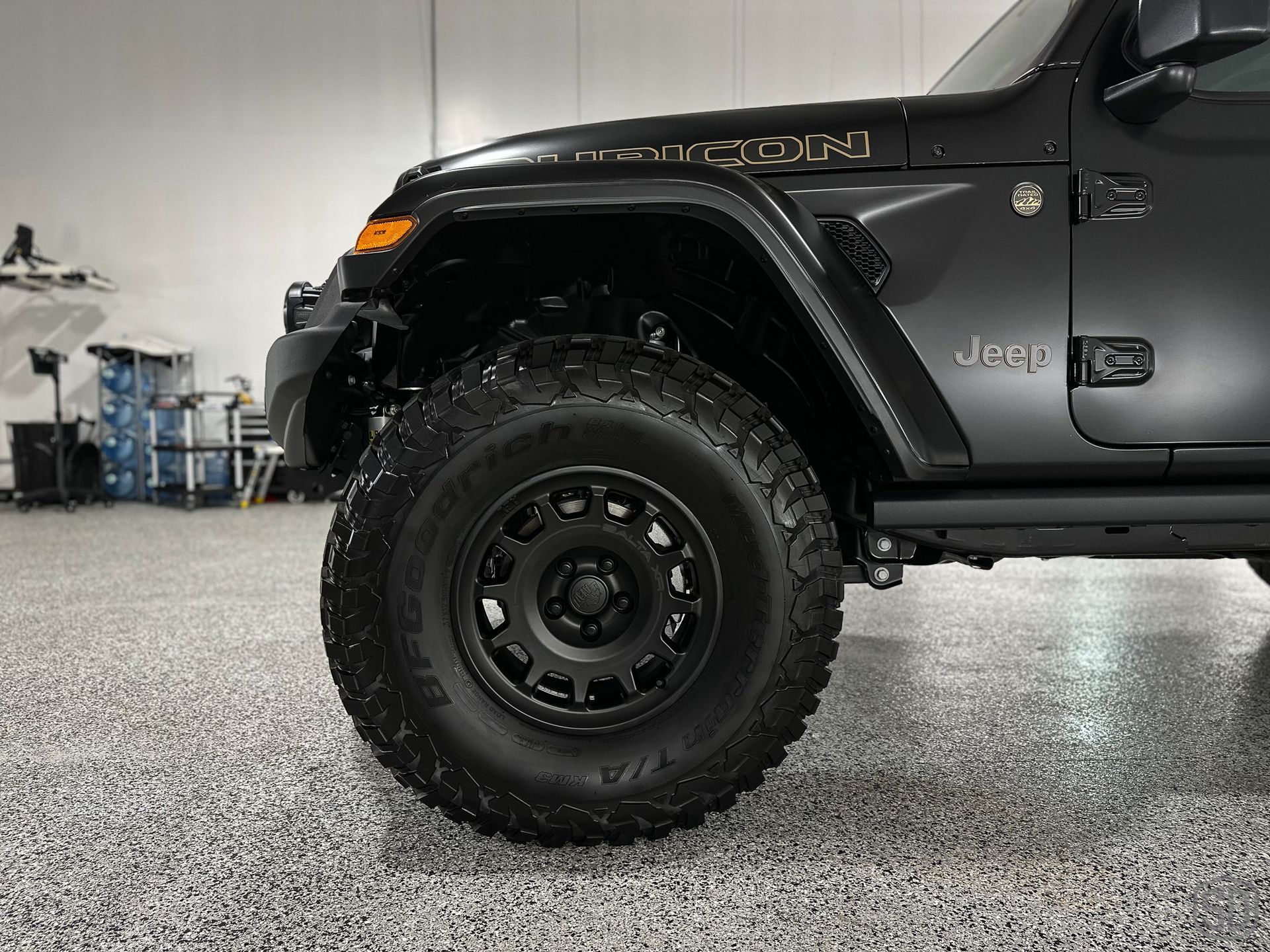 A black jeep wrangler is parked in a garage.