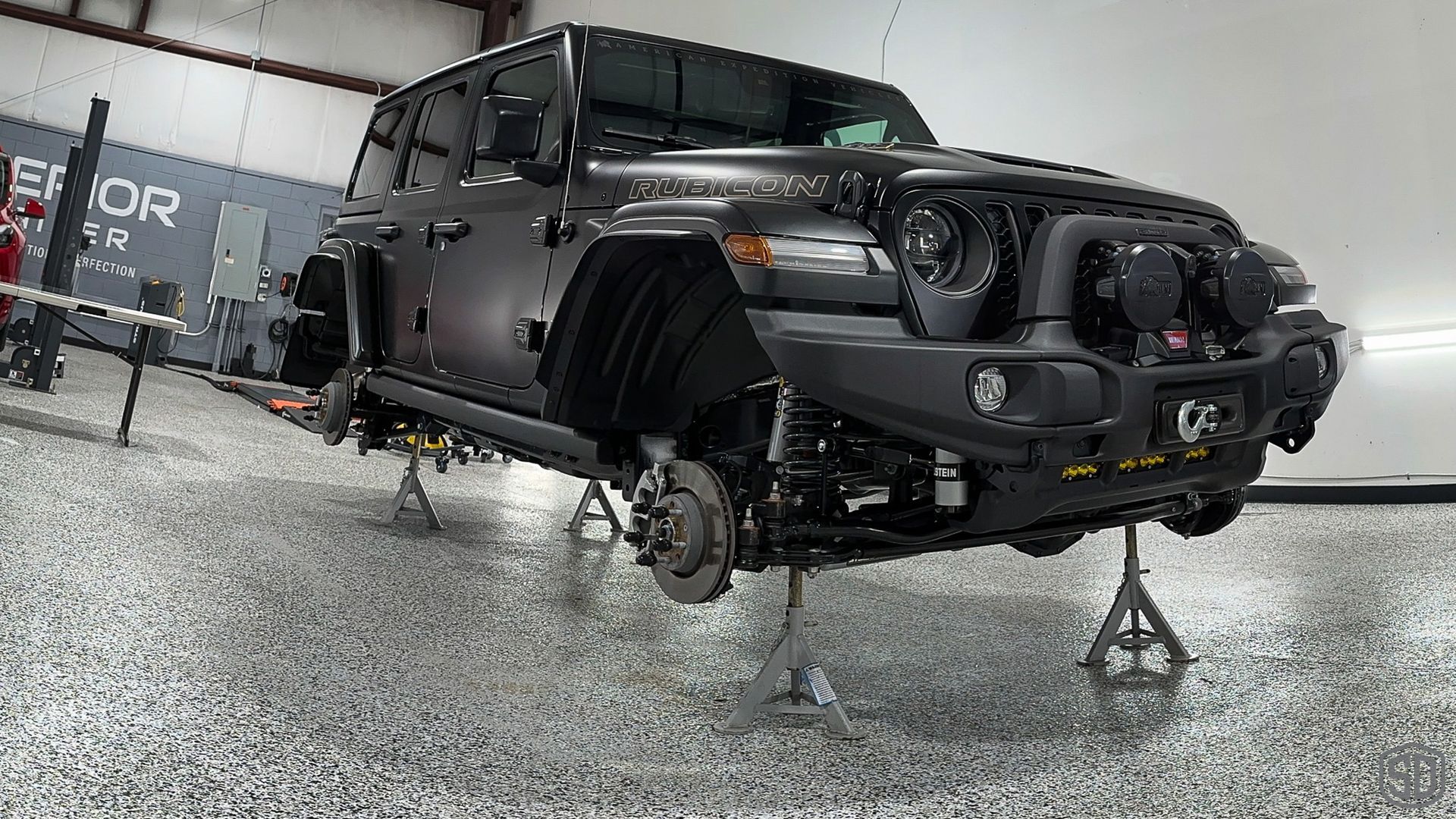 A black jeep is sitting on a concrete floor in a garage.