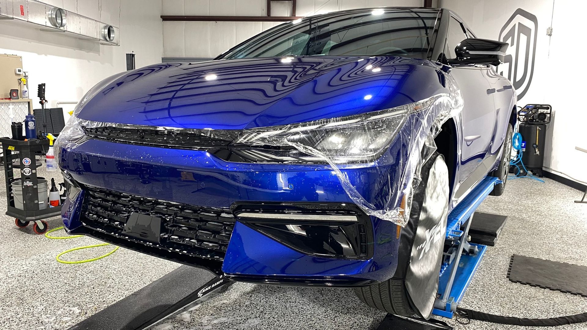 A blue car is sitting on a lift in a garage.