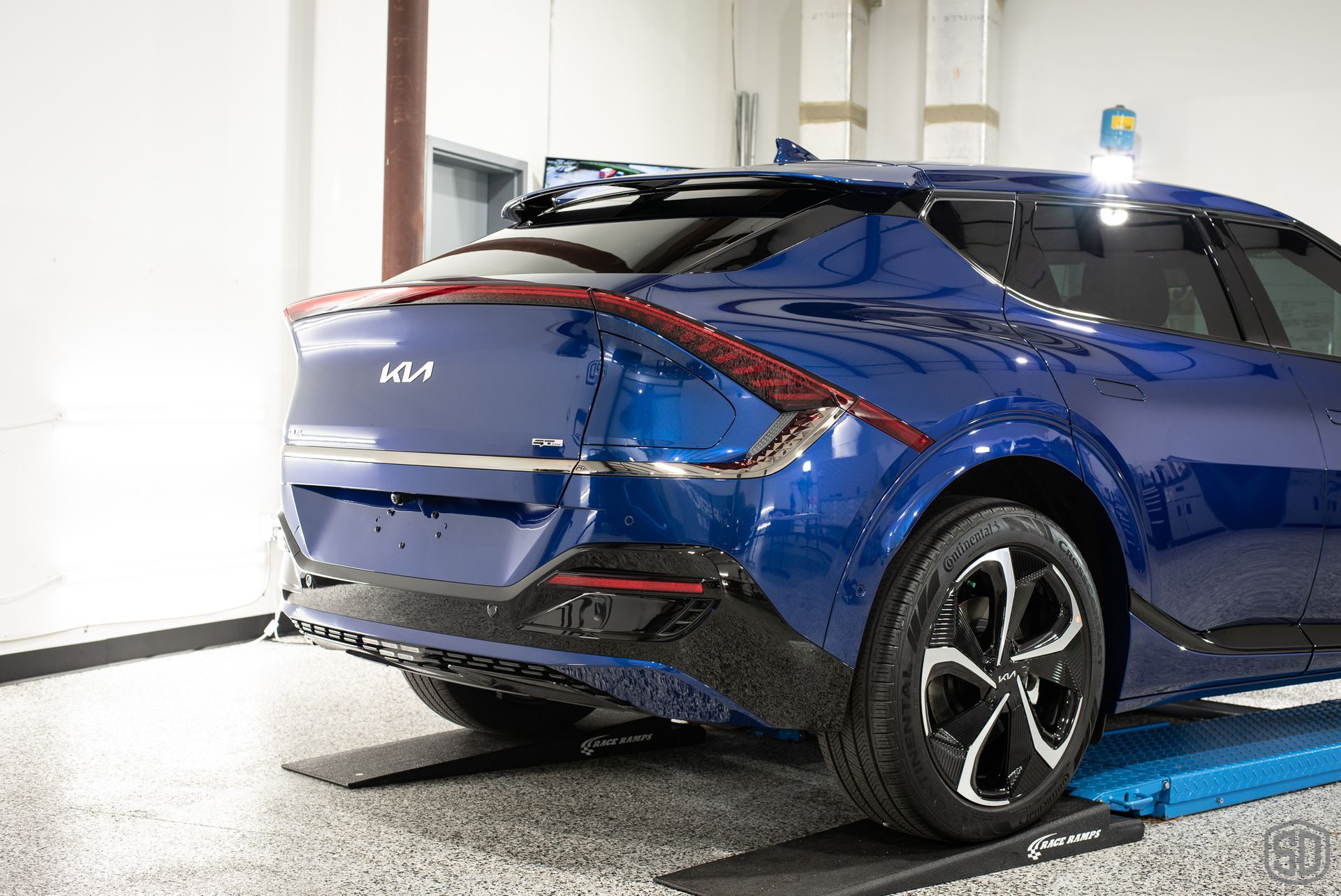 A blue car is sitting on a lift in a garage.
