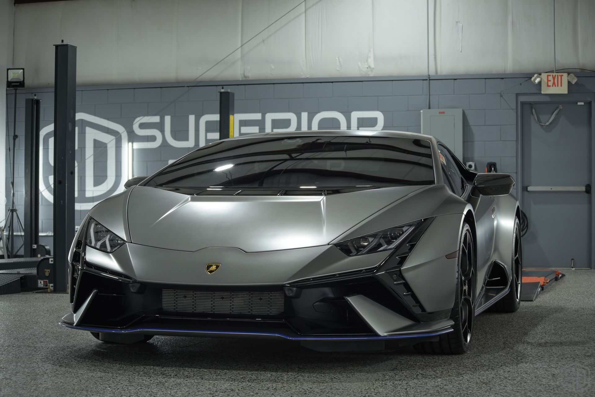 A gray lamborghini huracan is parked in a garage.