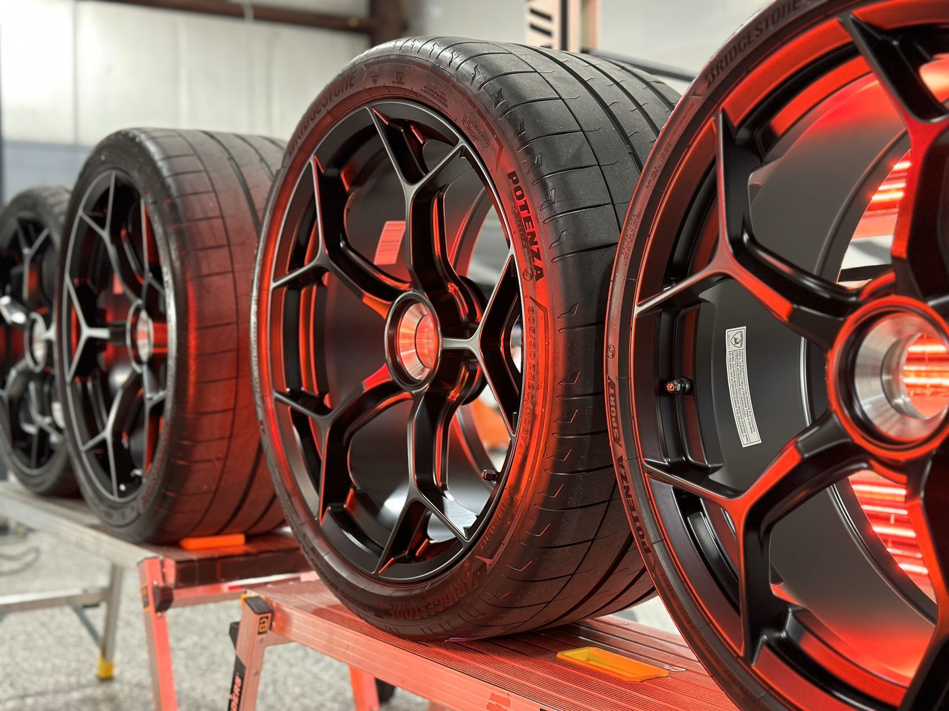 A row of wheels and tires are lined up on a table.