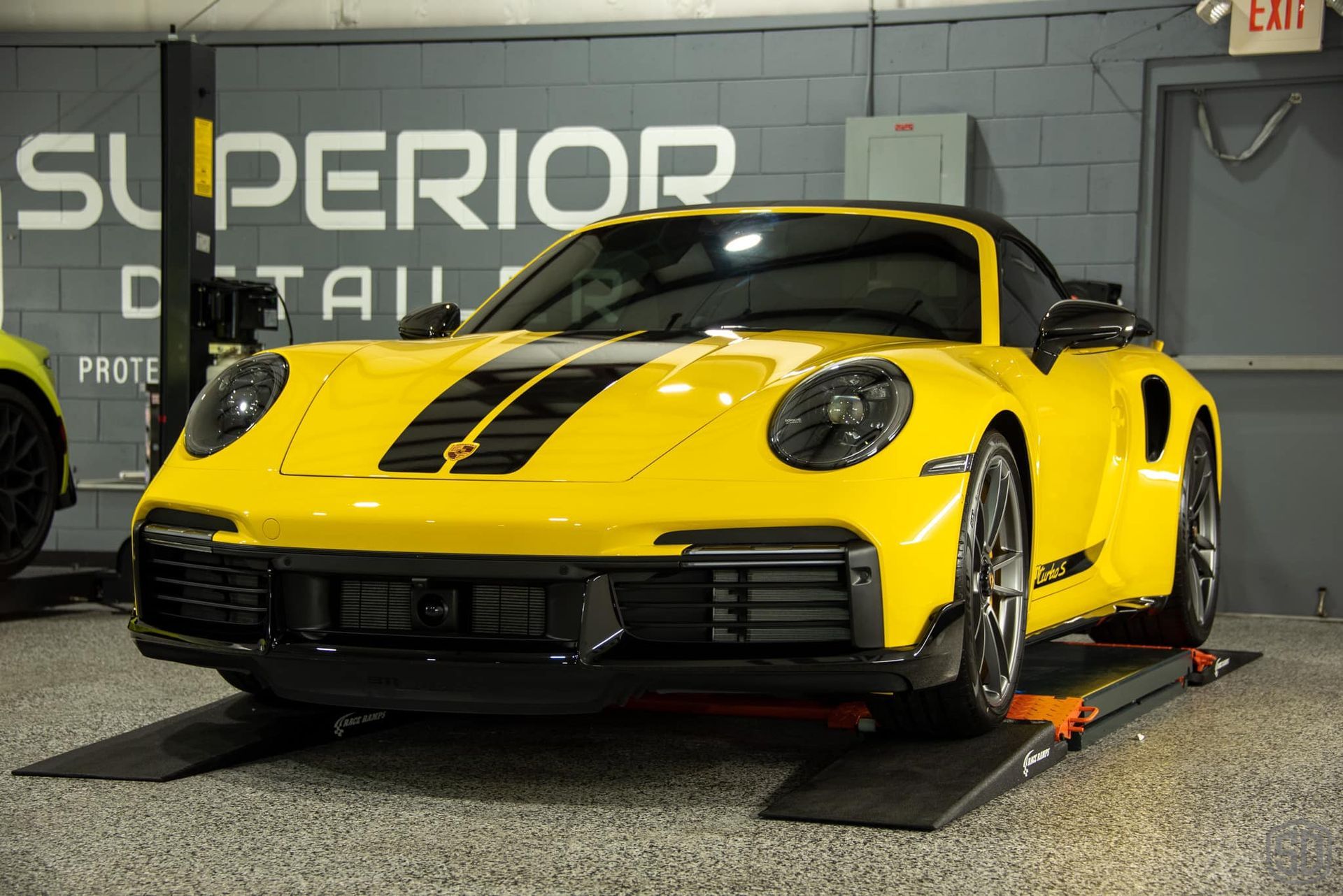 A yellow sports car is parked on a ramp in a garage.