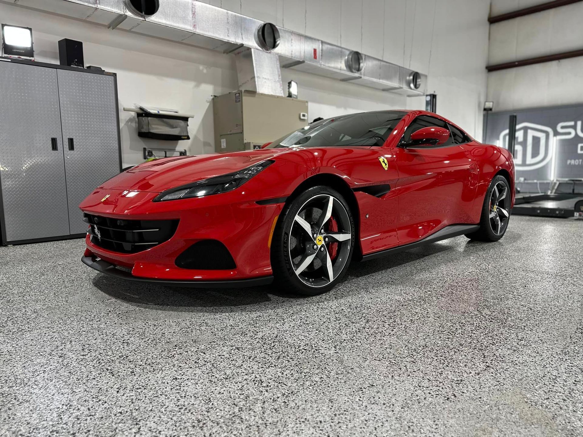 A red ferrari is parked in a garage.