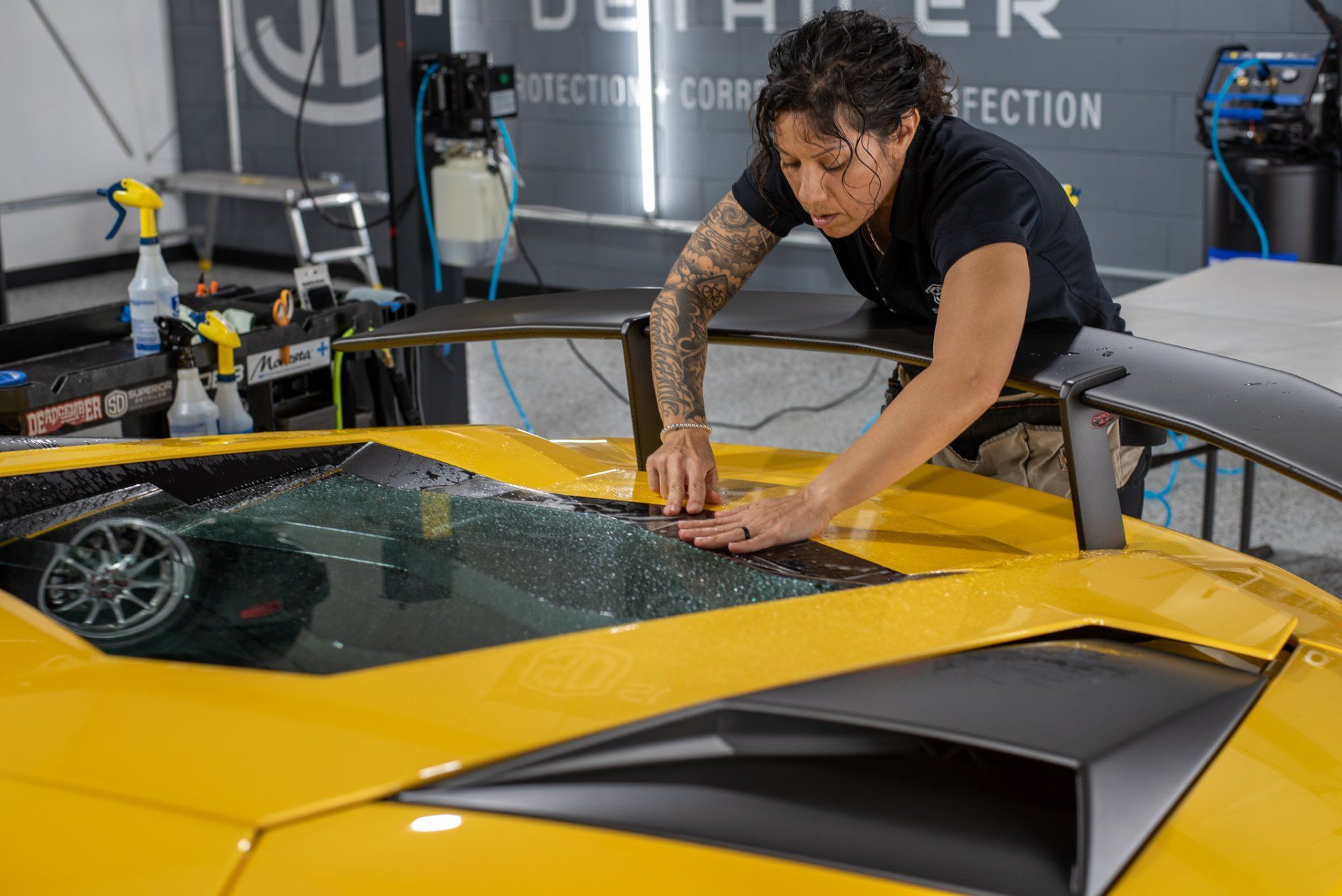 A man is working on a yellow sports car in a garage.
