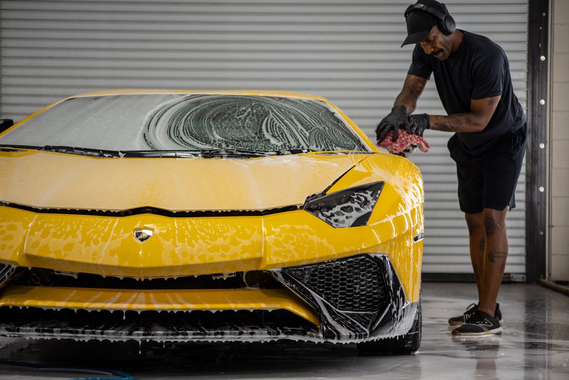 A man is washing a yellow lamborghini aventador in a garage.