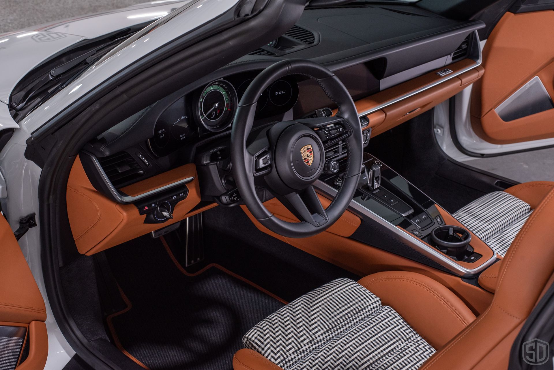 The interior of a white porsche 911 with brown seats and a steering wheel.
