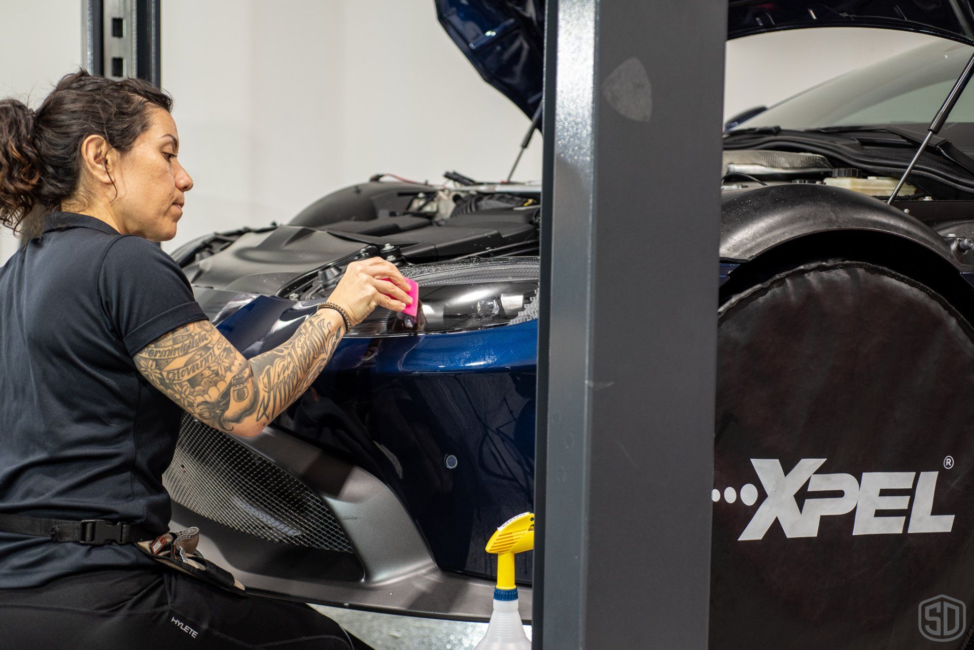 A woman is working on a car in a garage.