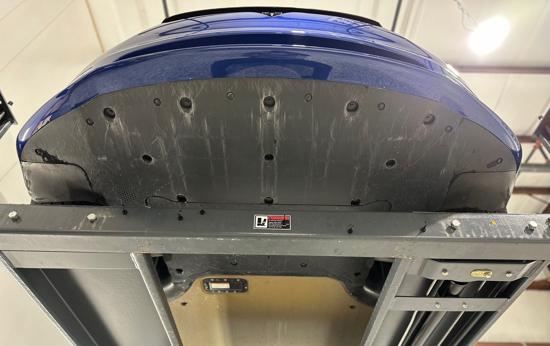 A blue car is sitting on a lift in a garage.