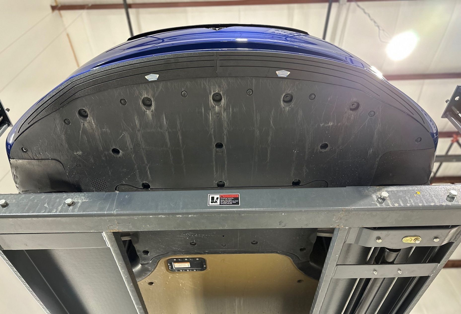 A blue car is sitting on a lift in a garage.