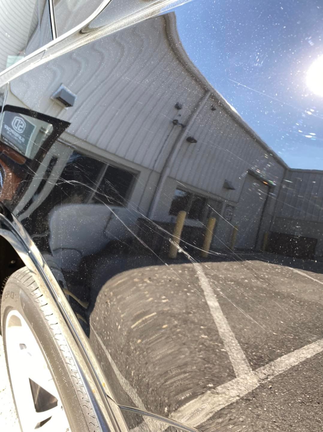 A black car with a reflection of a building in the windshield